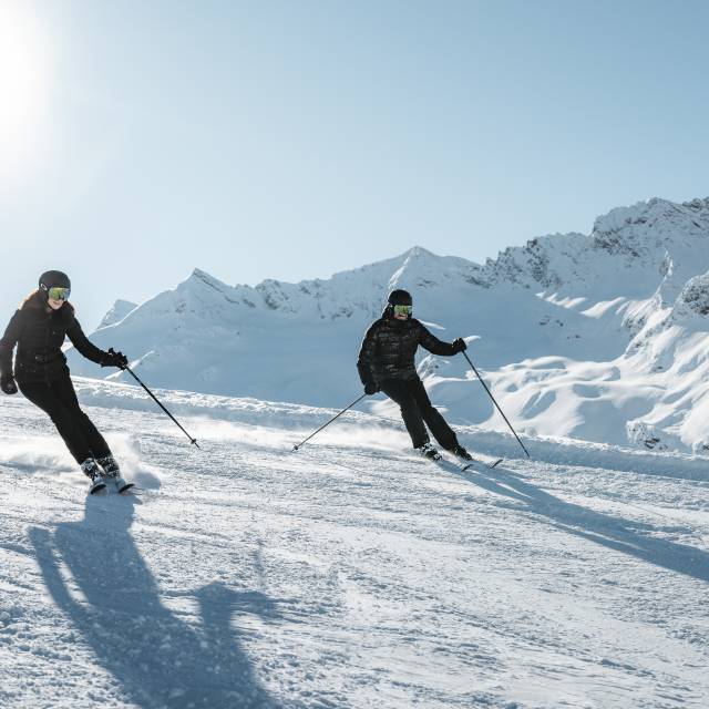 Skifahrer auf sonniger Piste in verschneiter Berglandschaft